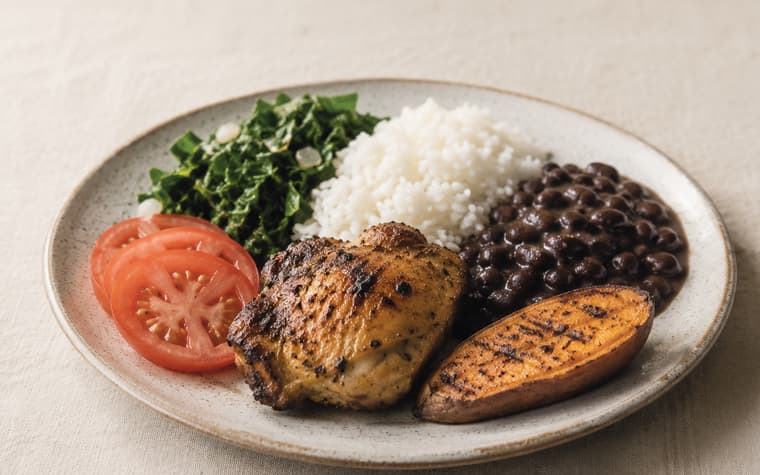 Prato com frango grelhado, arroz, feijão-preto, couve refogada, tomate e batata-doce assada